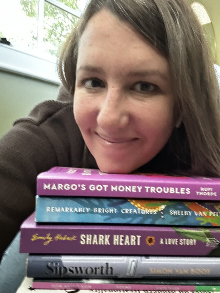 Carrie smiling with a stack of books