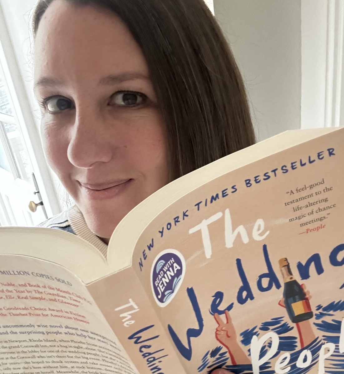 Carrie smiling behind an open book